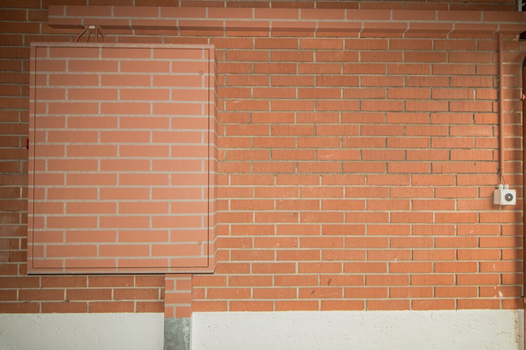 Backsteinwand mit einer im gleichen Ziegelmuster bemalten Revisionsklappe