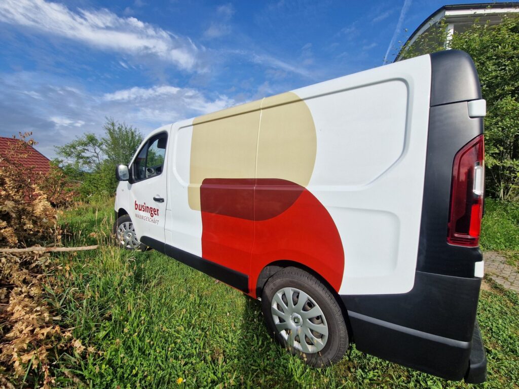 Weisser Firmenwagen mit Businger-Logo und farbigen Kreisflächen auf der Seitenwand