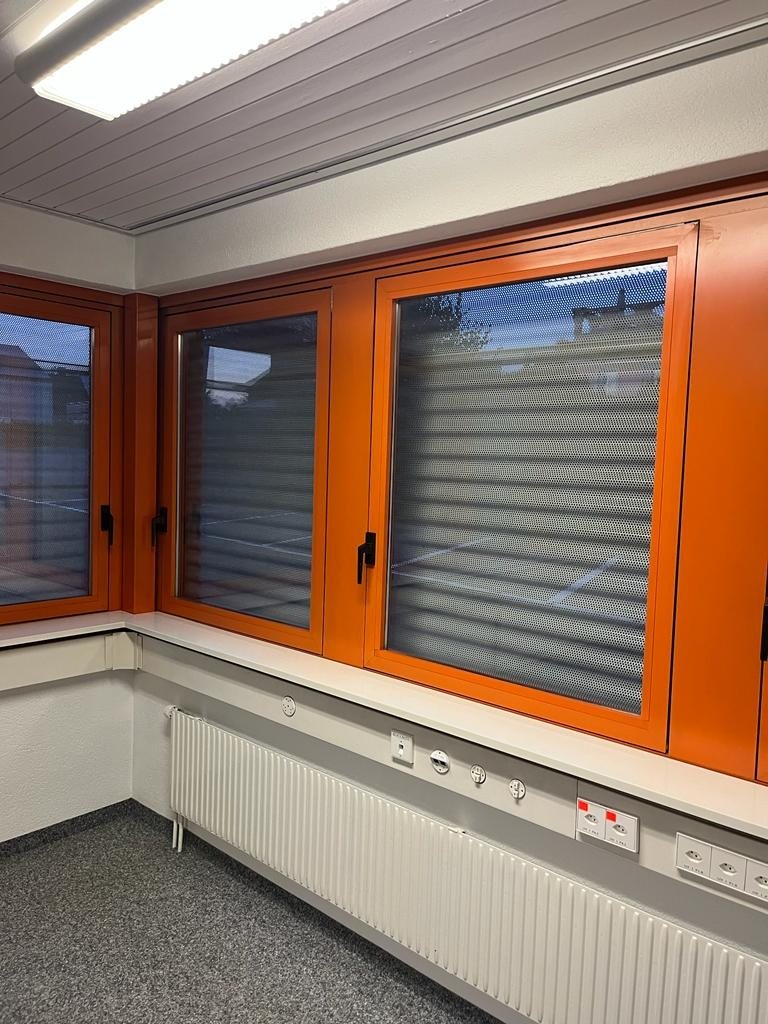 Büroraum mit orange lackierten Fensterrahmen und weissem Heizkörper
