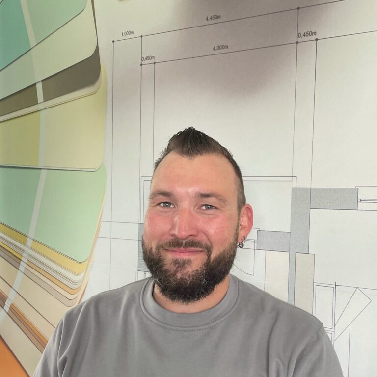 Andreas Stöckli vor einer Wand mit Farbfächern und Bauplan