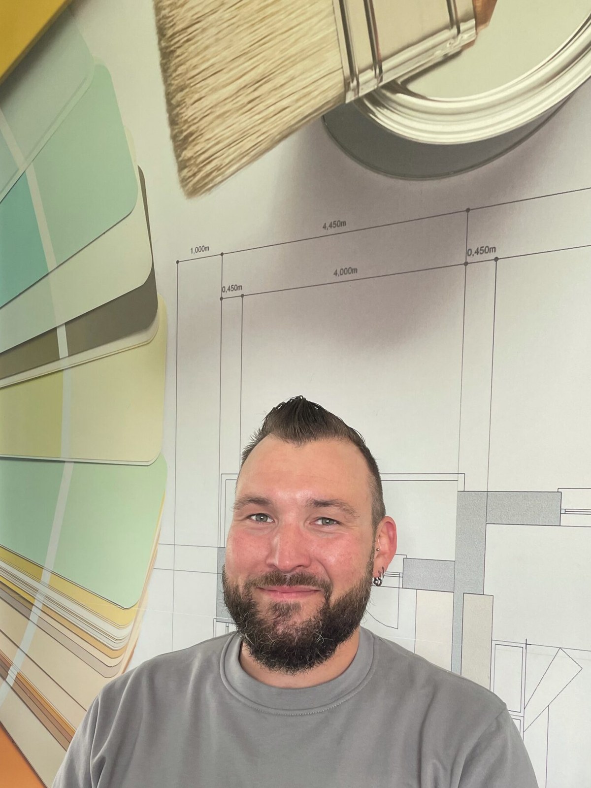 Andreas Stöckli vor einer Wand mit Farbfächern und Bauplan