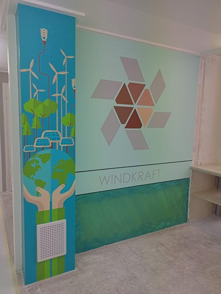 Illustrierte Windräder und Erdkugel auf blauer Säule neben einer mintgrünen Wand mit Rautenmuster