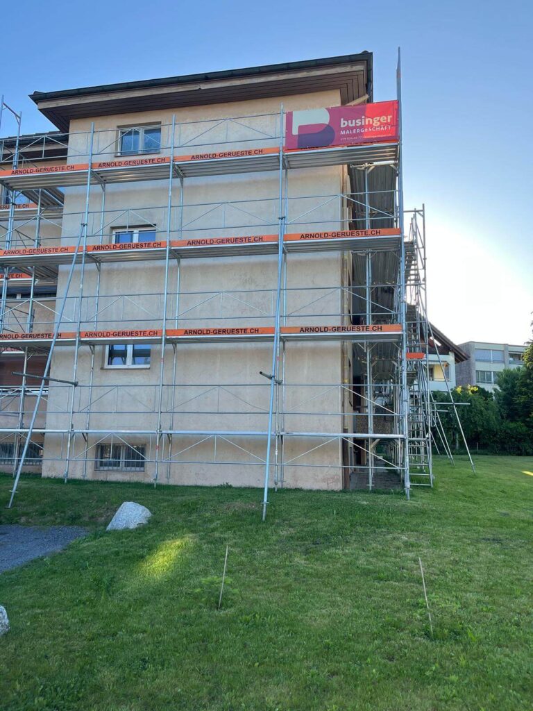 Vollständig eingerüstetes Wohnhaus mit roter Businger-Blache am obersten Gerüstgang