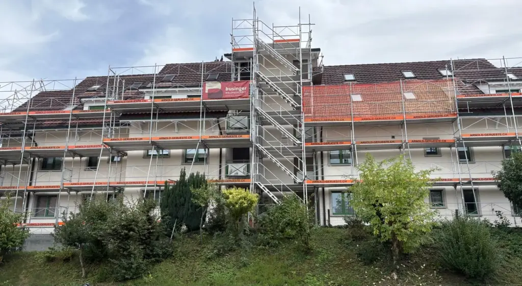 Eingerüstetes Mehrfamilienhaus mit Businger-Blache am Gerüst während der Fassadenrenovation