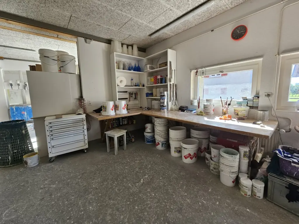 Arbeitsplatz in der Werkstatt von Businger Malergeschäft mit Farbkübeln, Pinseln und Werkzeugregal am Fenster