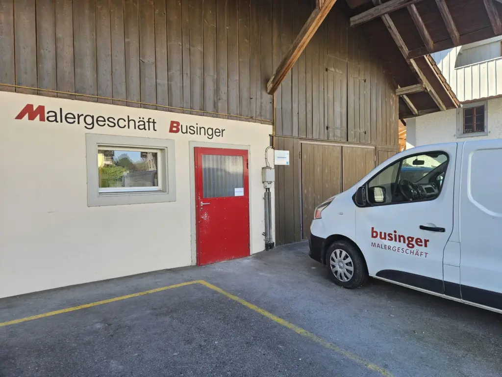 Eingang der Werkstatt von Businger Malergeschäft an der Hauptstrasse 3 in Rottenschwil mit roter Tür und Firmenwagen